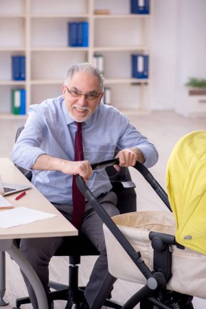 Téléchargez les photos : Un vieil homme d'affaires qui s'occupe d'un nouveau-né au bureau - en image libre de droit