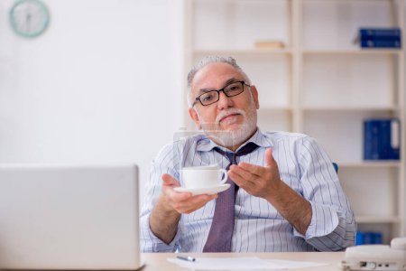 Téléchargez les photos : Vieil employé boire du café pendant la pause - en image libre de droit