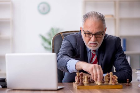 Téléchargez les photos : Ancien employé jouant aux échecs sur le lieu de travail - en image libre de droit