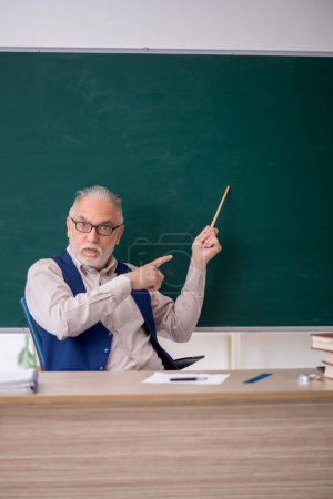 Photo for Old teacher in front of green board - Royalty Free Image