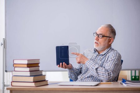 Foto de Viejo profesor sugiriendo libro en el aula - Imagen libre de derechos