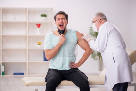 Photo for Young patient visiting old male doctor in vaccination concept - Royalty Free Image