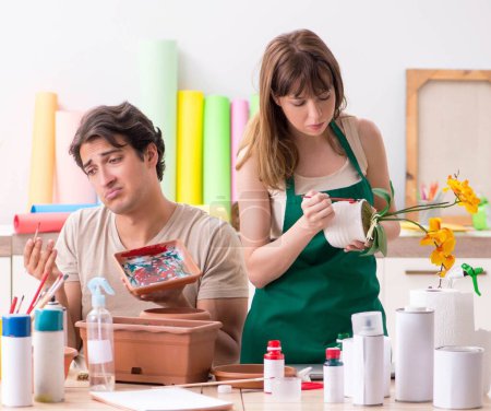Téléchargez les photos : Le couple décorer des pots en atelier pendant la classe - en image libre de droit