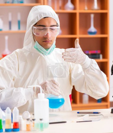 Téléchargez les photos : Le jeune biochimiste portant une combinaison de protection travaillant dans le laboratoire - en image libre de droit
