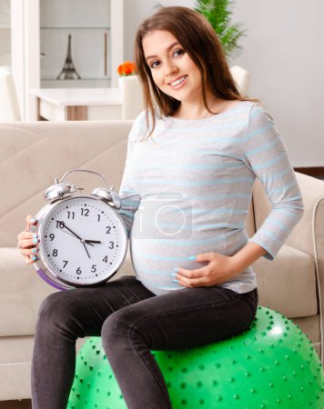 Photo for The young pregnant woman doing sport exercises at home - Royalty Free Image