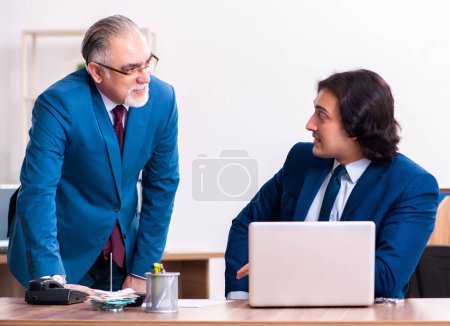 Téléchargez les photos : Les jeunes et les vieux employés qui travaillent ensemble au bureau - en image libre de droit