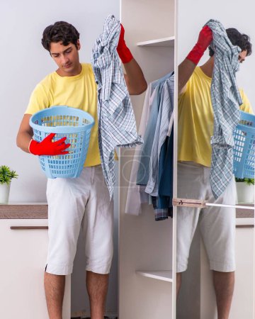 Téléchargez les photos : Le jeune homme beau nettoyer dans la chambre - en image libre de droit