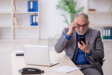 Foto de Viejo empleado hablando por teléfono en la oficina - Imagen libre de derechos