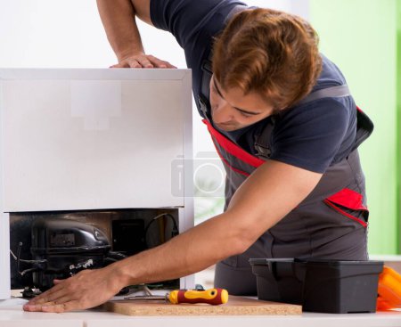Photo for The young handsome contractor repairing fridge - Royalty Free Image