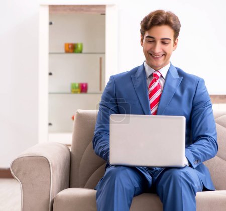 Téléchargez les photos : Le jeune homme d'affaires travaillant à la maison assis sur le canapé - en image libre de droit