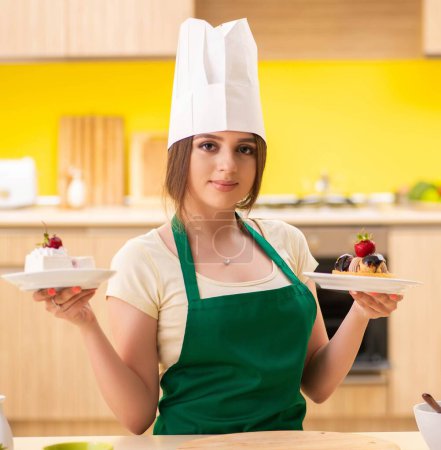 Téléchargez les photos : Le jeune cuisinier cuisine des gâteaux dans la cuisine - en image libre de droit