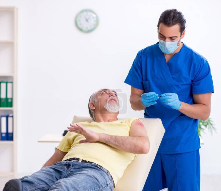 Foto de Hombre viejo lesionado visitando a un traumatólogo médico masculino - Imagen libre de derechos