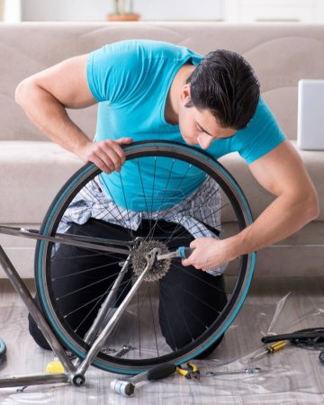 Photo for The young man repairing bicycle at home - Royalty Free Image