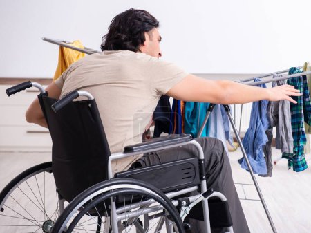 Foto de El joven en silla de ruedas haciendo planchado en casa - Imagen libre de derechos
