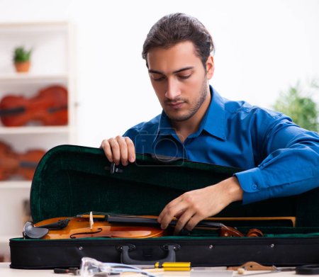 Photo for Young male repairman repairing the violin - Royalty Free Image