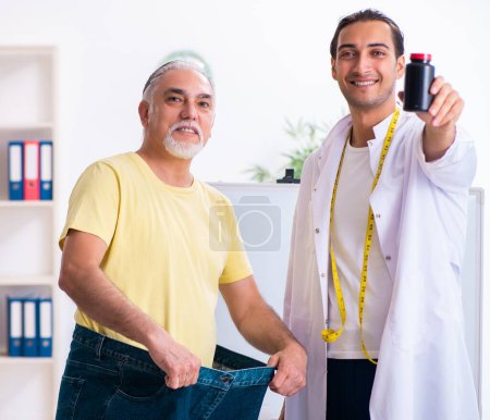 Foto de El médico dietista y paciente feliz con pantalones grandes - Imagen libre de derechos