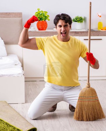 Téléchargez les photos : Le jeune homme beau nettoyer dans la chambre - en image libre de droit