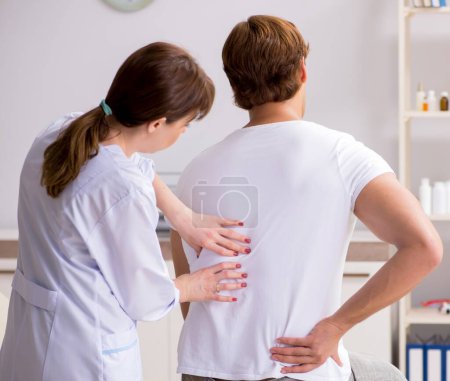 The male patient visiting young female doctor chiropractor