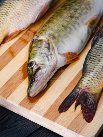 Téléchargez les photos : Le poisson non cuit en planche à découper dans le concept de préparation des repas - en image libre de droit