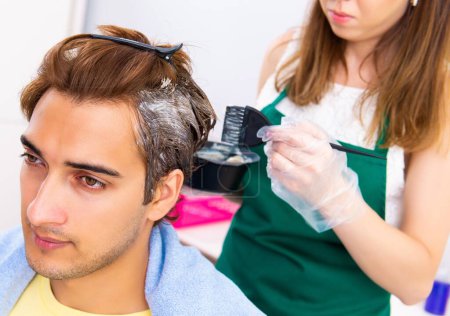 Foto de La peluquera mujer aplicando tinte al cabello del hombre - Imagen libre de derechos