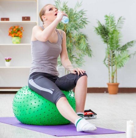 Téléchargez les photos : La jeune femme exerçant avec la balle de stabilité dans la salle de gym - en image libre de droit