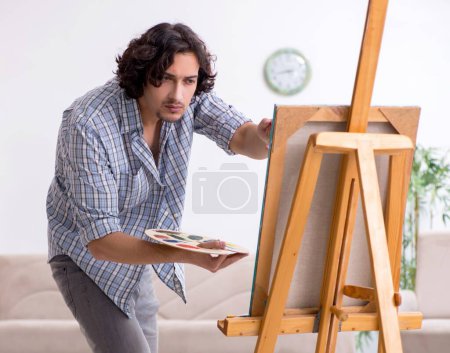 Téléchargez les photos : Le jeune homme beau qui aime peindre à la maison - en image libre de droit