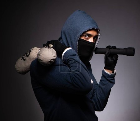 Téléchargez les photos : Le jeune gangster à capuche sur fond gris - en image libre de droit