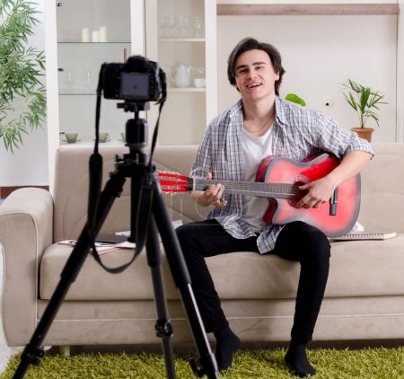 Téléchargez les photos : Le jeune guitariste enregistre une vidéo pour son blog - en image libre de droit