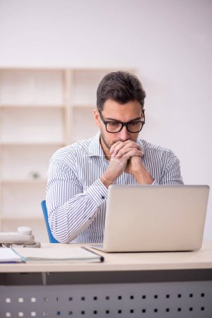 Photo for Young male employee sitting at workplace - Royalty Free Image