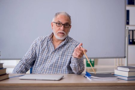 Photo for Old teacher sitting in front of whiteboard - Royalty Free Image