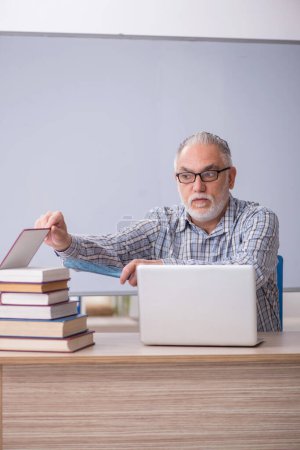 Foto de Viejo profesor sentado frente a la pizarra - Imagen libre de derechos