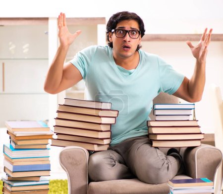 Téléchargez les photos : The male student with many books at home - en image libre de droit