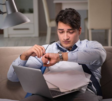 Foto de El hombre de negocios adicto al trabajo trabajando hasta tarde en casa - Imagen libre de derechos