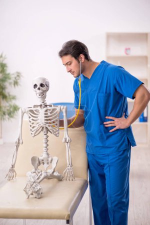 Téléchargez les photos : Young doctor and skeleton patient at the hospital - en image libre de droit