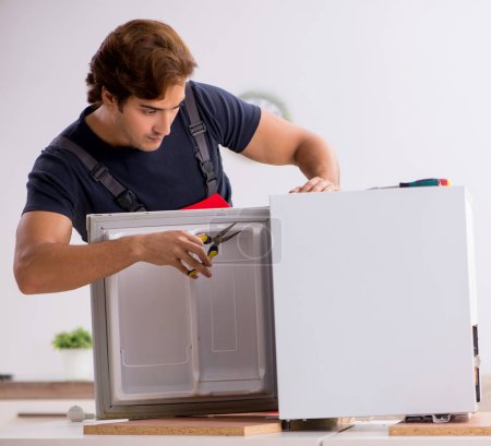 Photo for The young handsome contractor repairing fridge - Royalty Free Image
