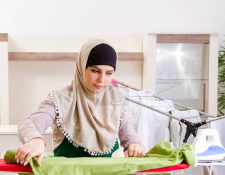 Photo for The woman in hijab doing clothing ironing at home - Royalty Free Image
