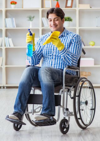 Téléchargez les photos : L'homme handicapé en fauteuil roulant nettoyage maison - en image libre de droit