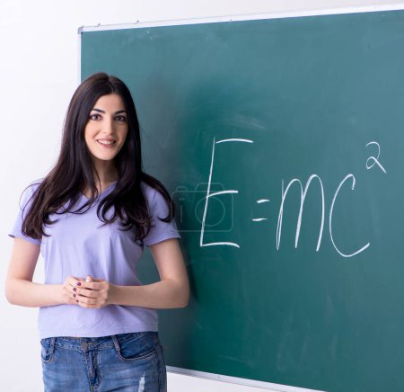 Foto de La joven profesora alumna frente al tablero verde - Imagen libre de derechos