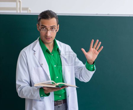 Photo for The young male chemist teacher in front of blackboard - Royalty Free Image