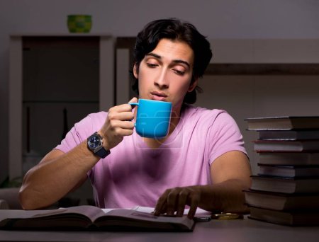 Foto de El estudiante guapo masculino que se prepara para los exámenes tarde en casa - Imagen libre de derechos