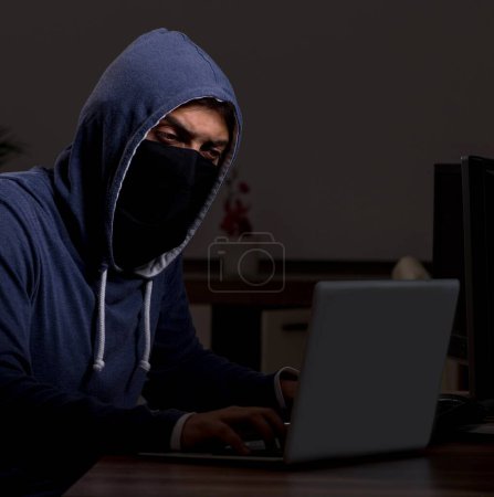 Téléchargez les photos : Pirate masculin piratage pare-feu de sécurité tard dans le bureau - en image libre de droit