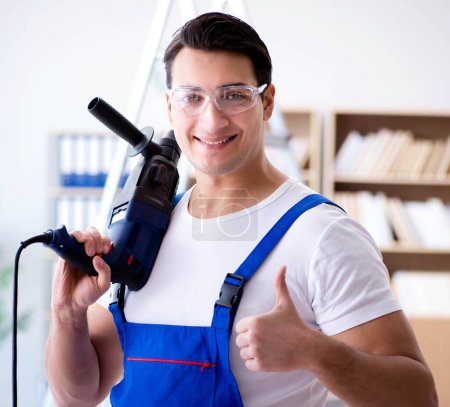 Foto de El reparador que trabaja con perforadora de perforación - Imagen libre de derechos