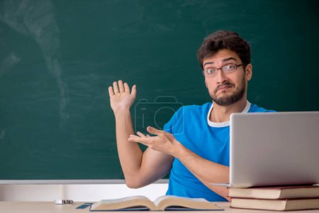 Téléchargez les photos : Jeune enseignant étudiant devant le green board - en image libre de droit