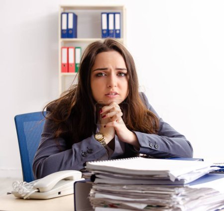Photo for The young female employee unhappy with excessive work - Royalty Free Image