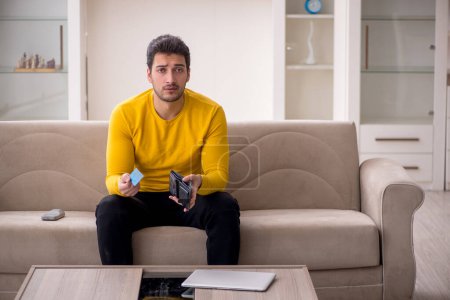 Téléchargez les photos : Young male student sitting at home in remuneration concept - en image libre de droit