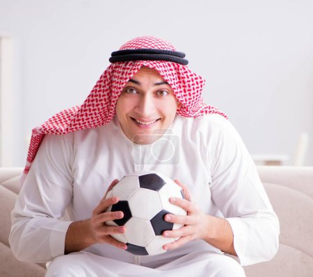 Foto de El joven árabe mirando fútbol sentado en el sofá - Imagen libre de derechos