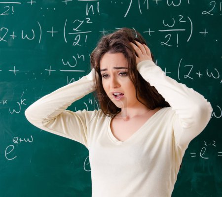 Photo for The young female math teacher in front of chalkboard - Royalty Free Image