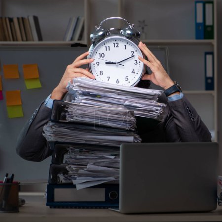 Téléchargez les photos : Le jeune employé masculin travaillant tard au bureau - en image libre de droit