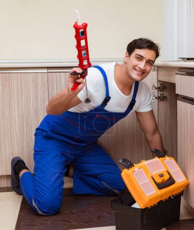 Photo for The young repairman working at the kitchen - Royalty Free Image