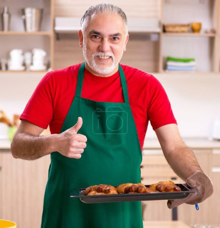 Téléchargez les photos : Le vieil homme boulanger travaillant dans la cuisine - en image libre de droit